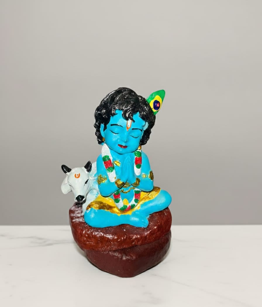 Colorful figurine of a deity with a cow on a white surface