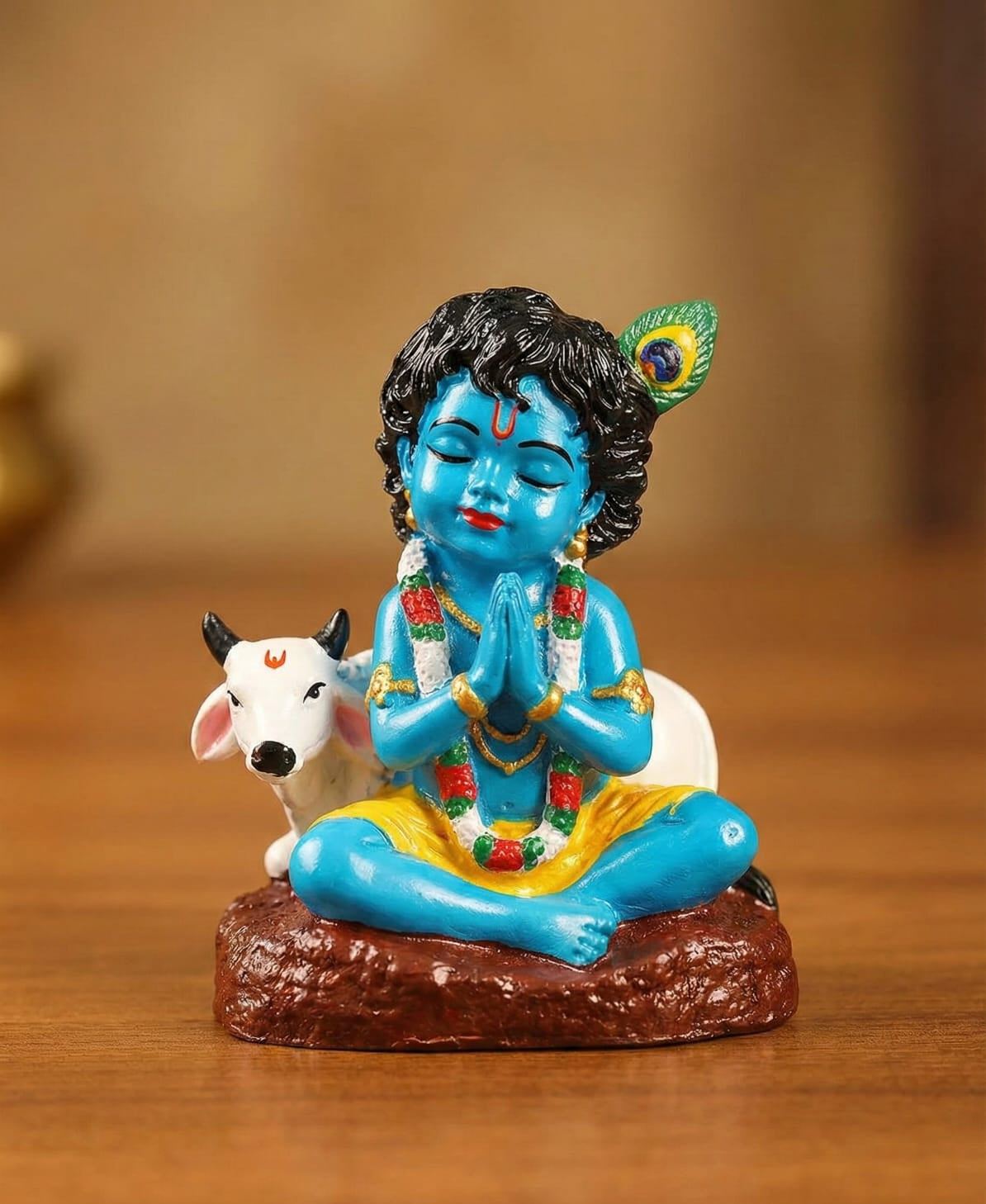 Colorful figurine of a deity with a cow on a wooden surface