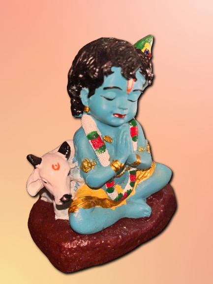 Decorative figurine of a blue-skinned deity with a cow on a pink background